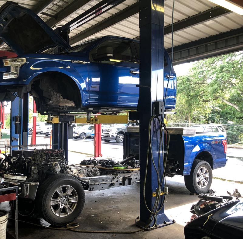 Blue truck in midair undergoing auto repair services