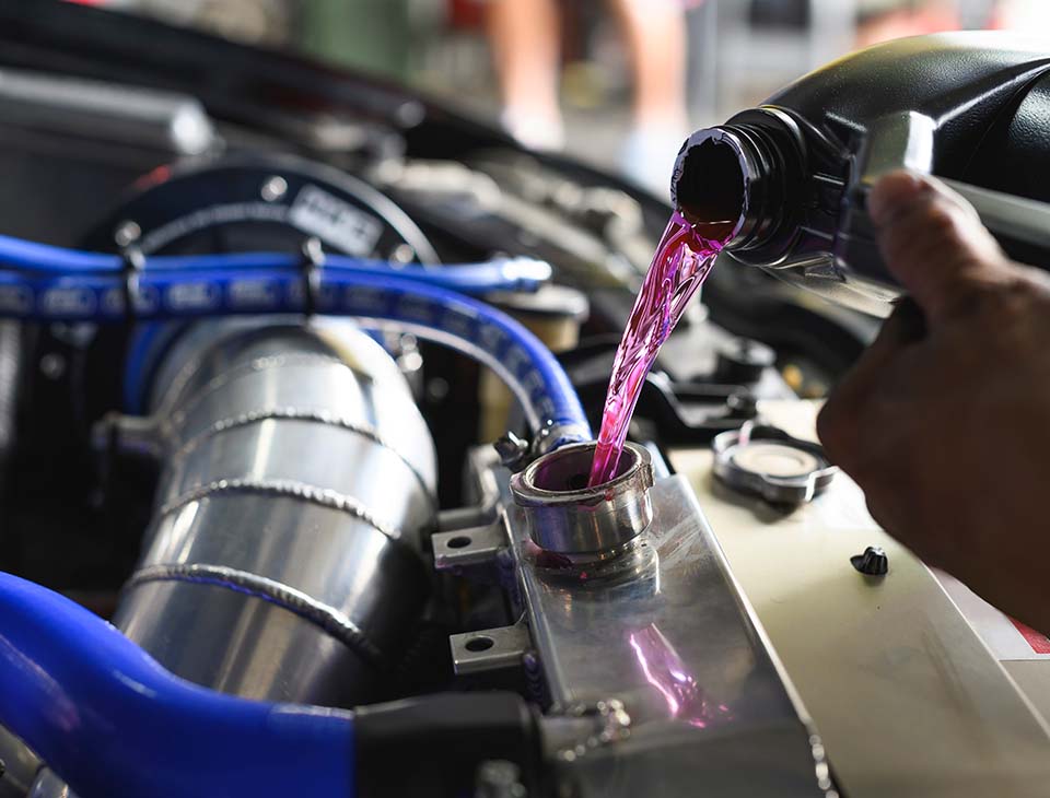 Auto mechanic filling Pre-mixed Super Long Life Coolant fluid in aluminum car radiator fill hole.