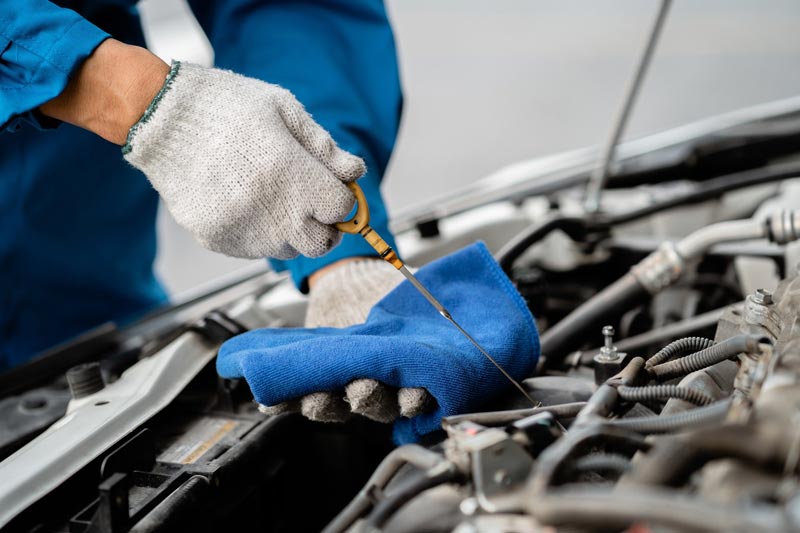 Close-up, a car mechanic checking the oil in a car's engine.
